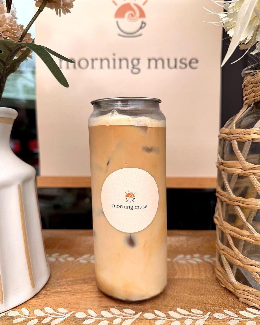 Brown sugar latte in a Morning Muse can over ice, on the branded backdrop