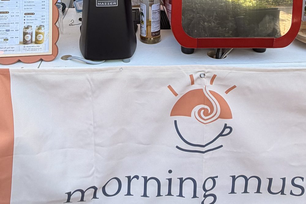 The Morning Muse pop-up cart: espresso machine, grinder, and the banner with our logo